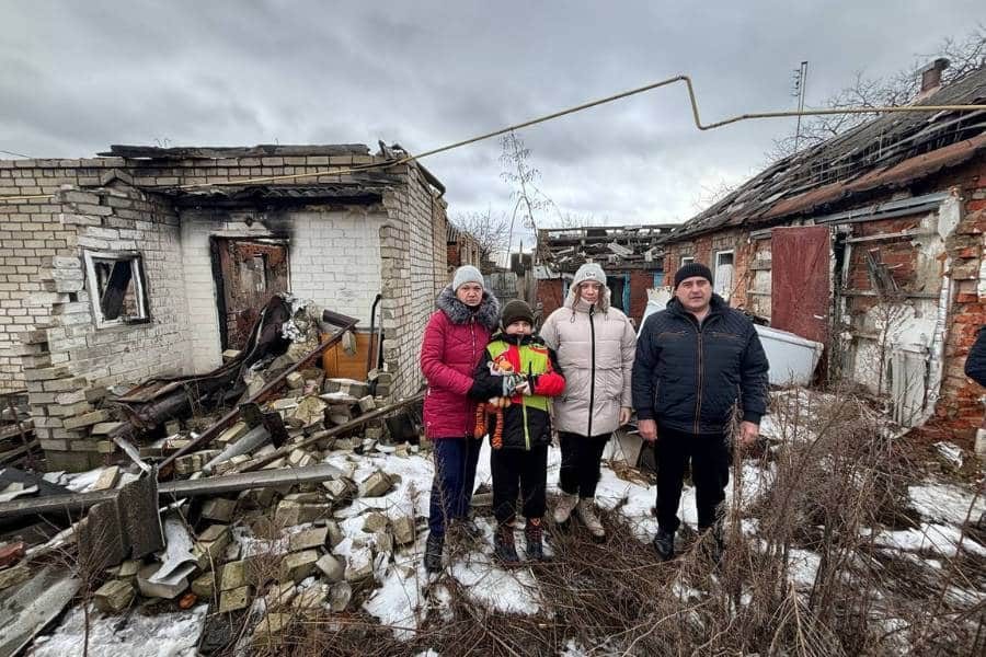 Ukrainian Family Standing in Front of Ruined Home.